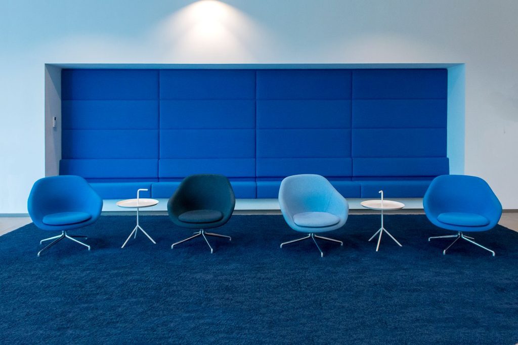 Office with blue chairs and tables on wall-to-wall carpet