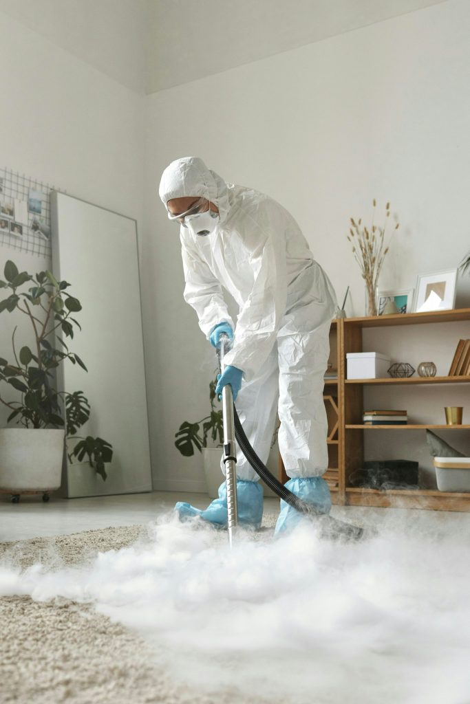 Cleaner in a protective suit deep cleaning a carpet