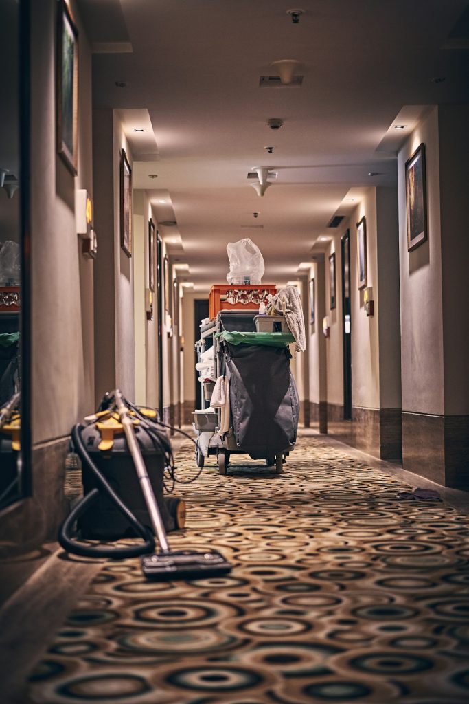 Housekeeping cart and vacuum in a carpeted hotel corridor