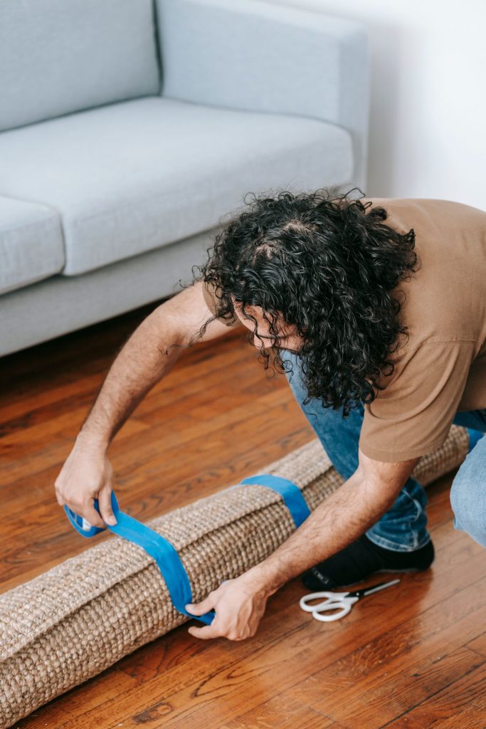 Man taping a rolled carpet in a living room