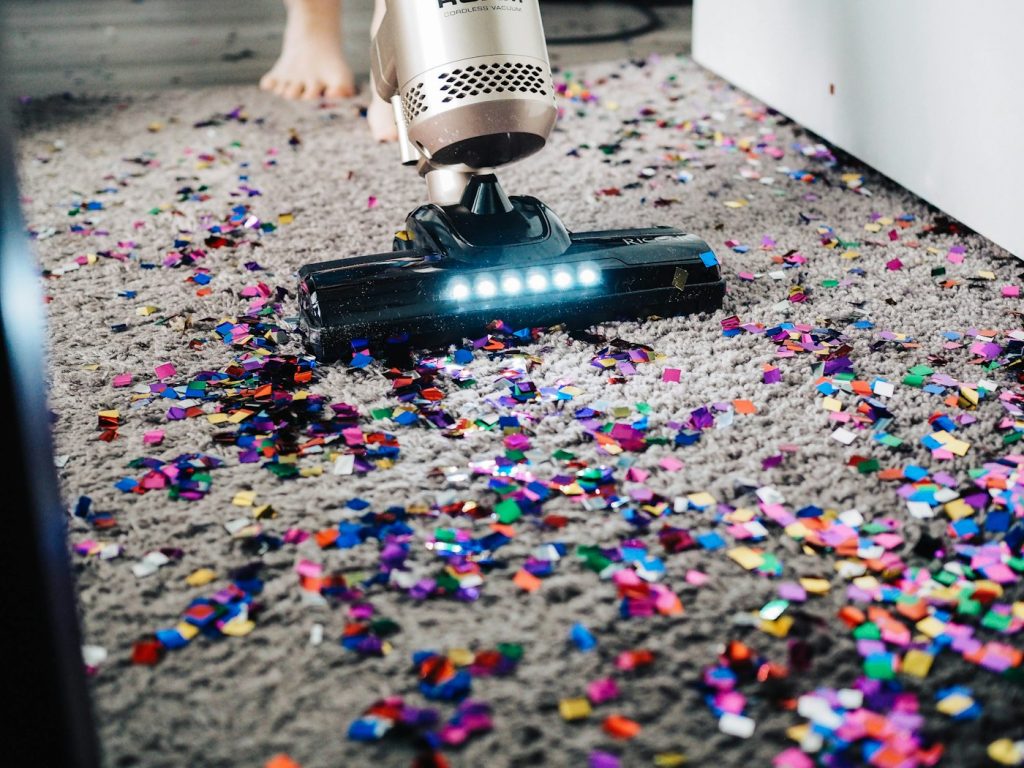 Person running a vacuum across a carpet before deep cleaning