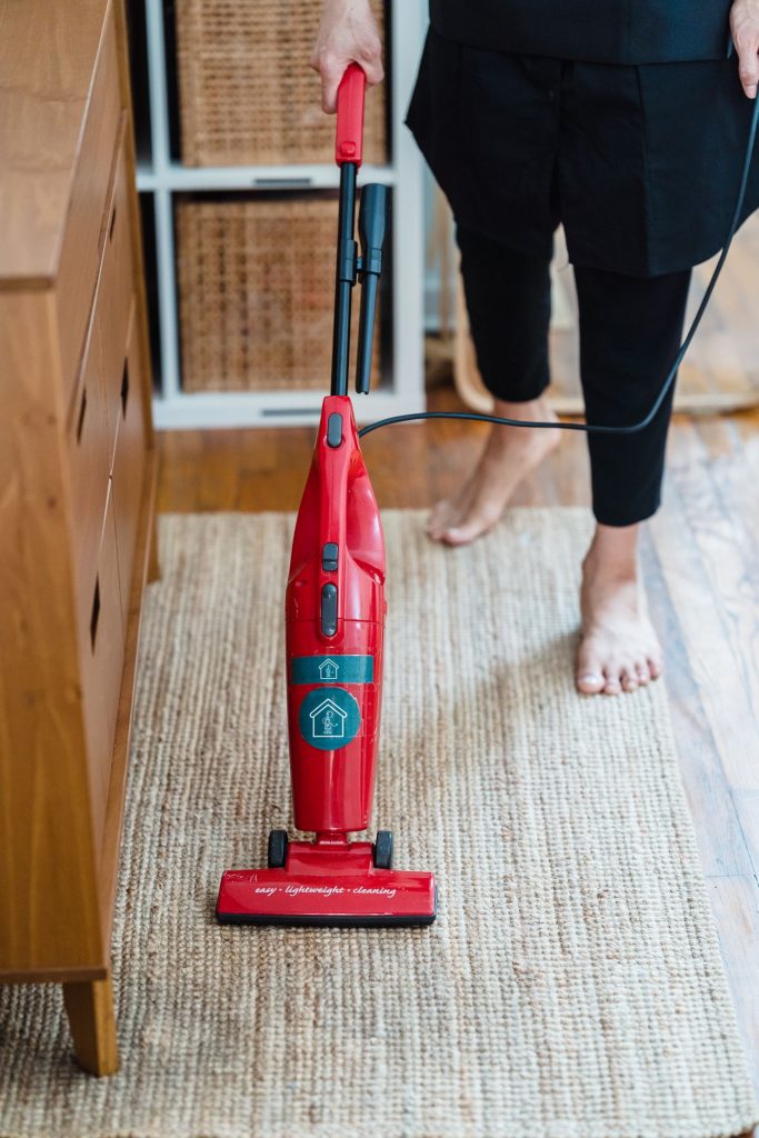 Person vacuuming wall-to-wall carpet in a modern room